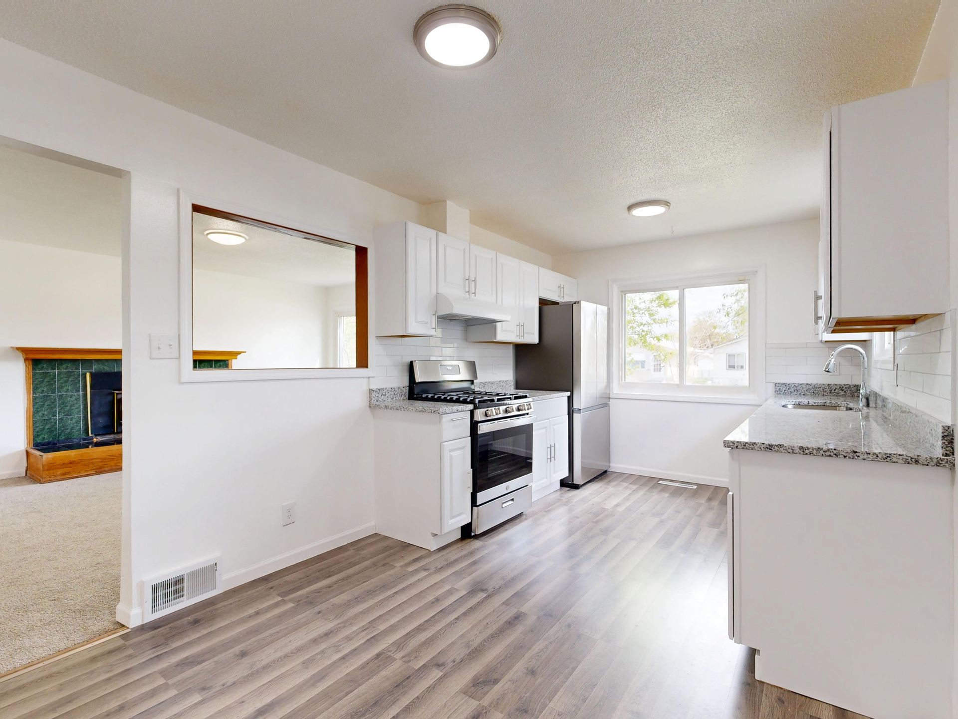 Renovated kitchen with white cabinets and hardwood floors